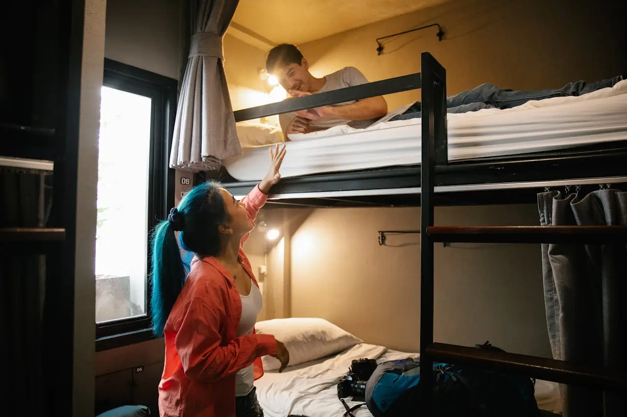 Young couple enjoying a cozy stay in a hostel bunk bed room, perfect for budget travel and bonding.